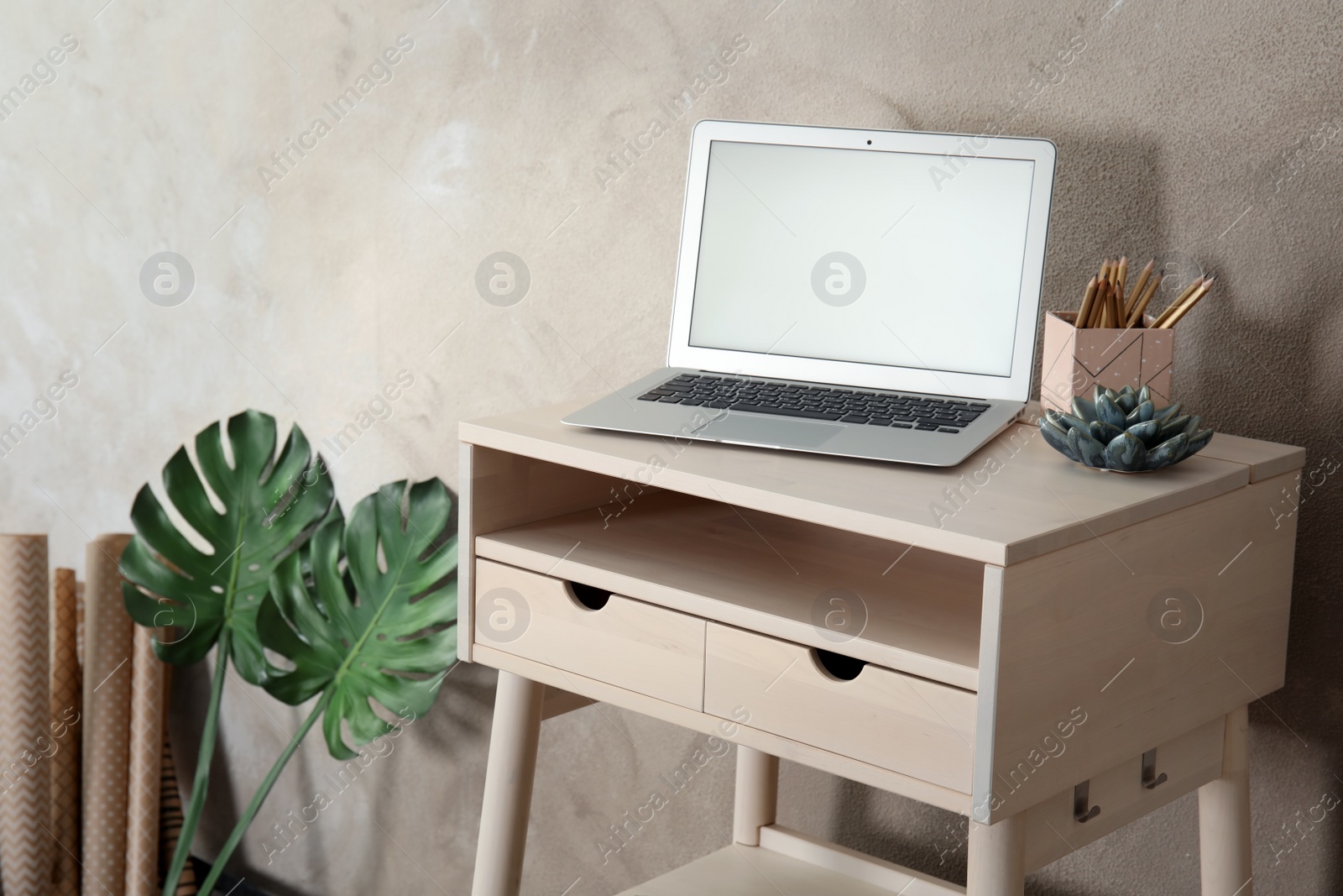 Photo of High wooden table with laptop as stand up workplace in modern interior