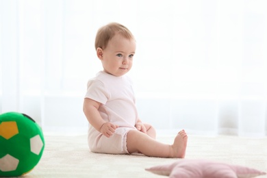 Cute baby sitting on floor indoors