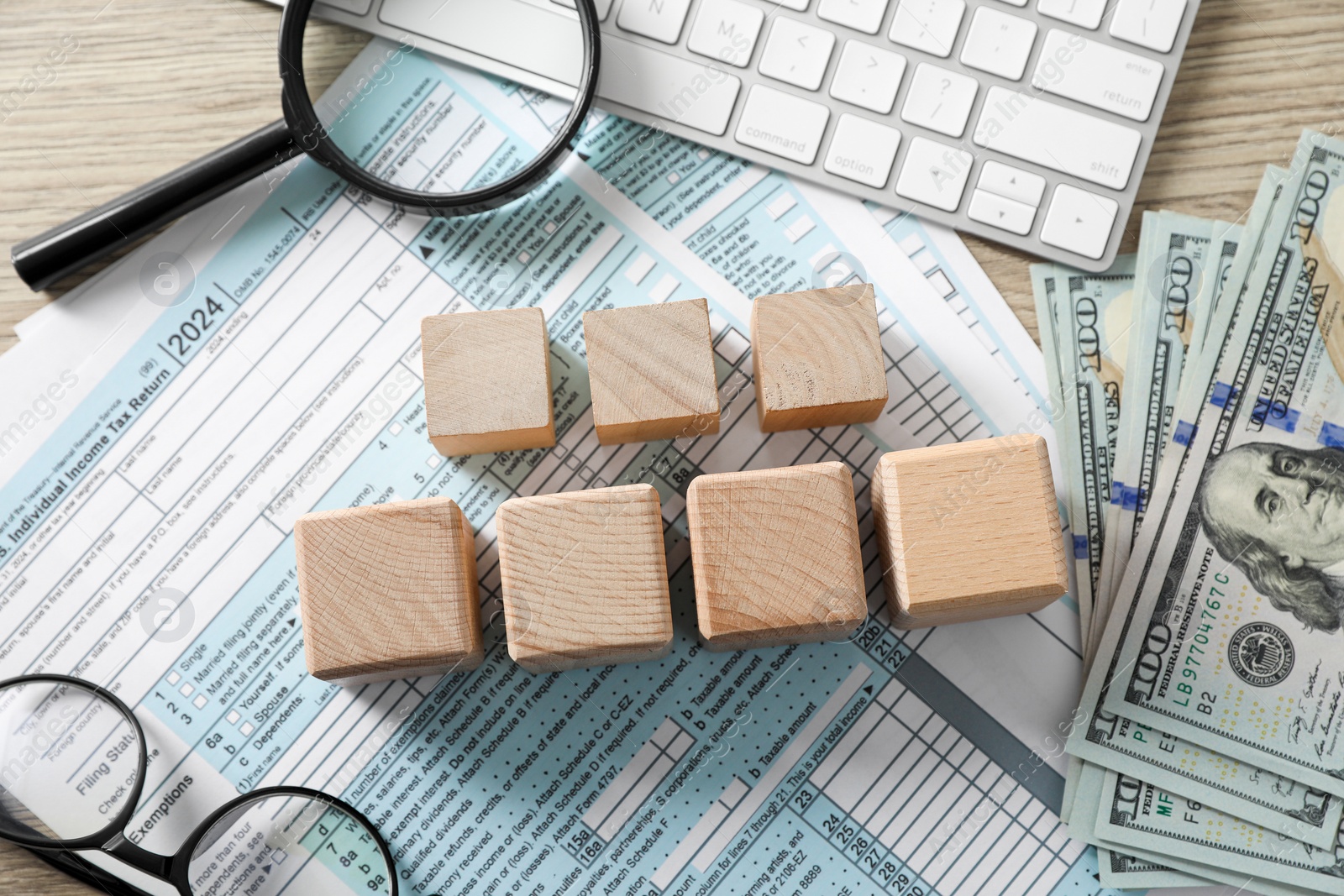 Photo of Taxes. Cubes, money, glasses and documents on light wooden table, flat lay