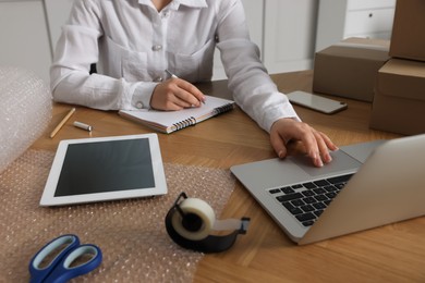 Photo of Seller working with laptop at table in office, closeup. Online store