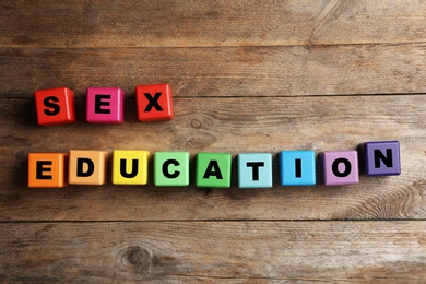 Photo of Colorful blocks with phrase "SEX EDUCATION" on wooden background, flat lay