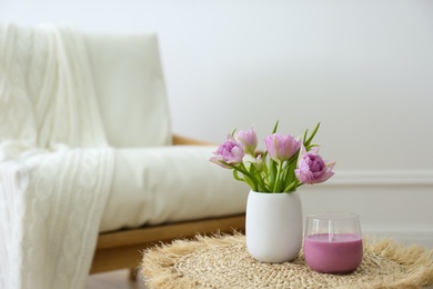 Photo of Vase with beautiful flowers and candle on table indoors, space for text. Interior elements