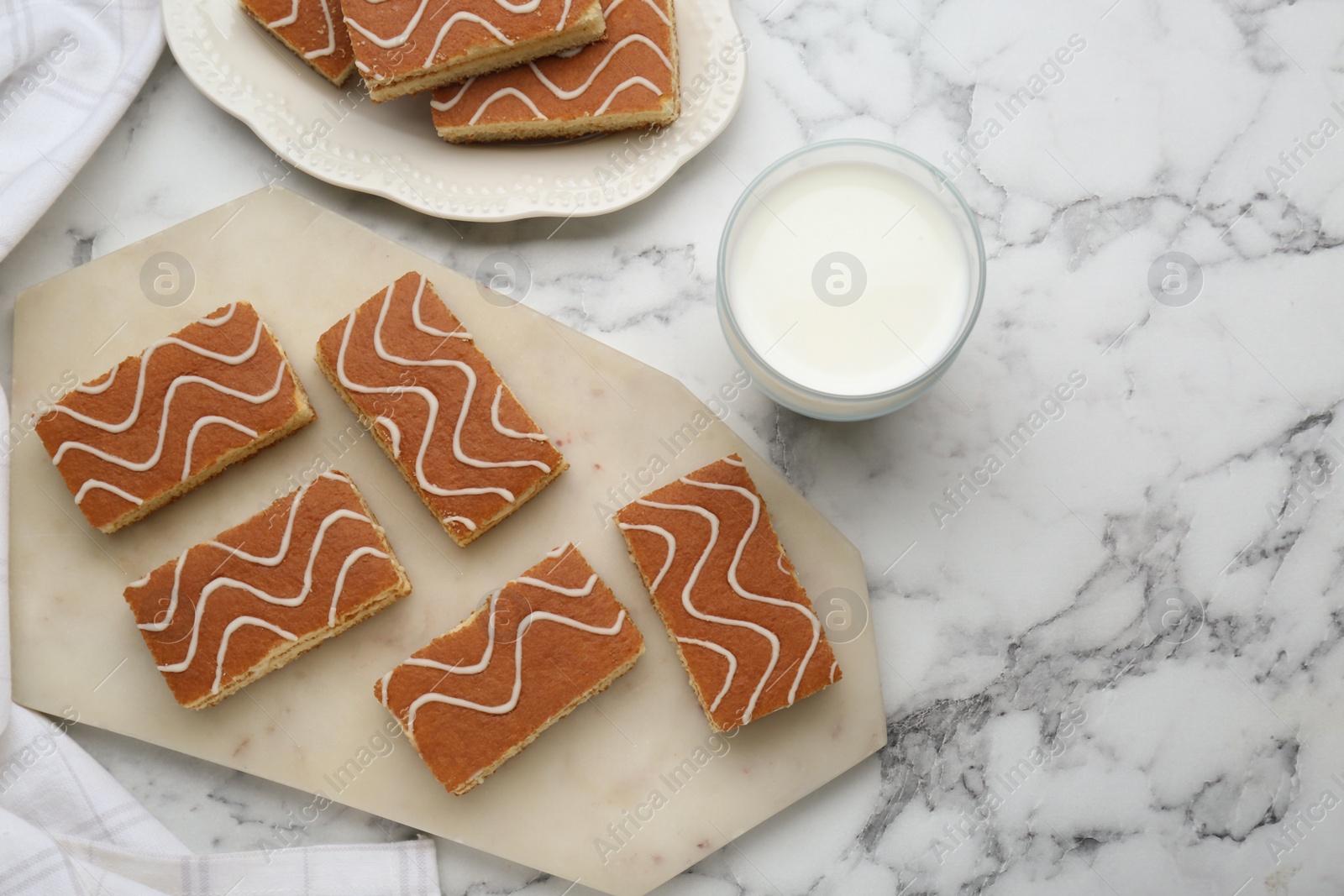 Photo of Tasty sponge cakes and milk on white marble table, flat lay. Space for text