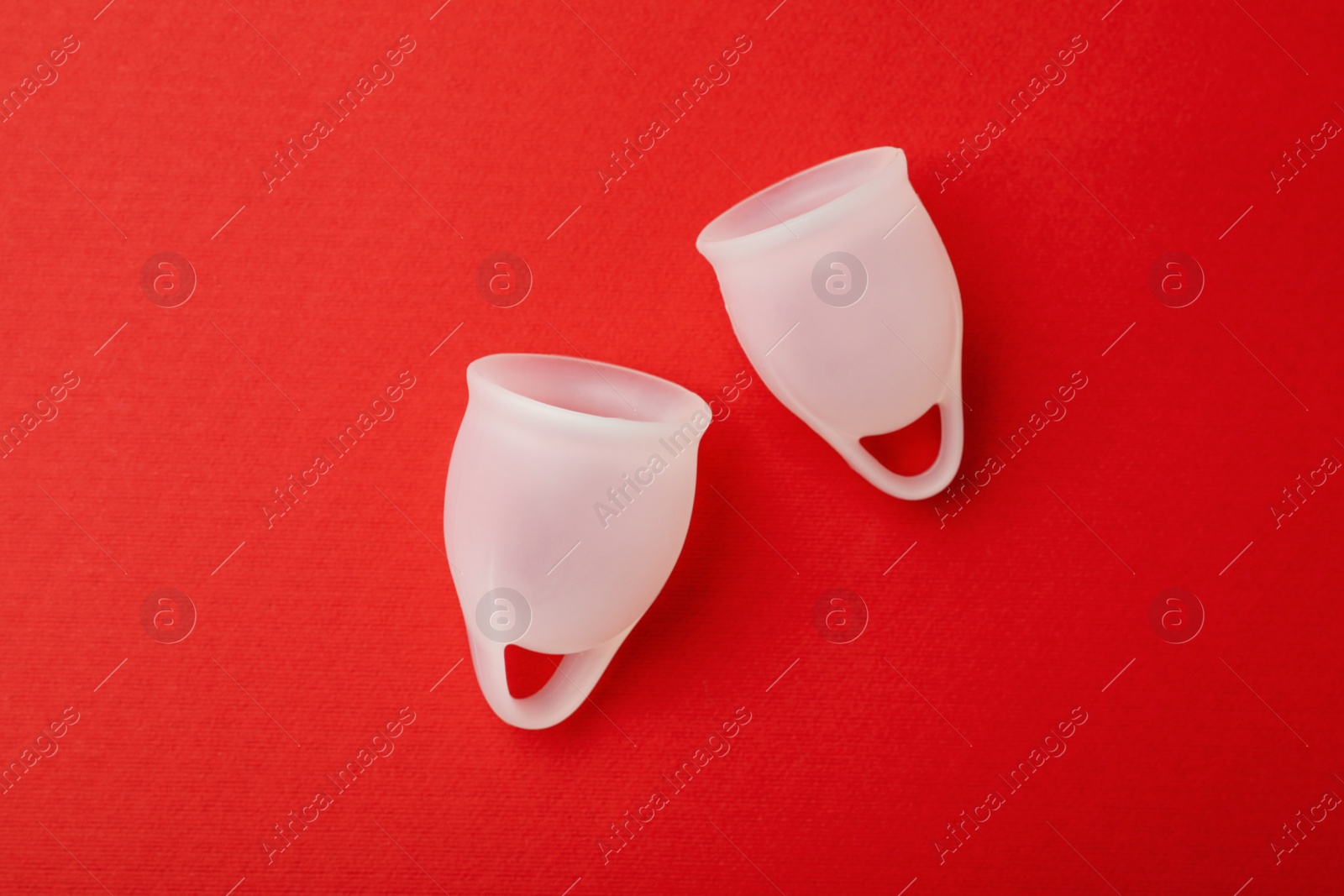 Photo of Menstrual cup on red background, flat lay