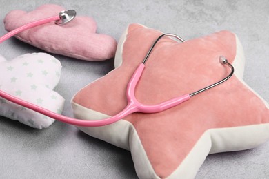 Photo of Pillows and stethoscope on gray background, closeup