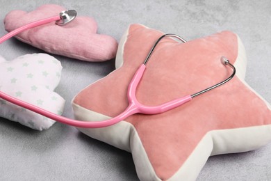 Pillows and stethoscope on gray background, closeup