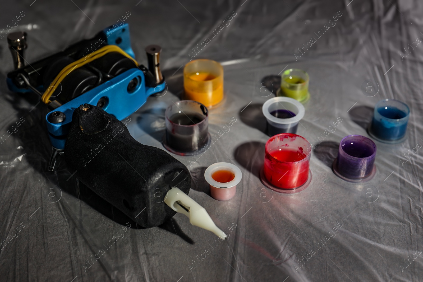 Photo of Caps with colorful inks and tattoo machine on table