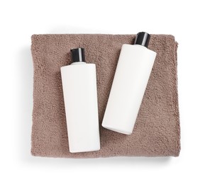 Soft brown terry towel and cosmetic bottles isolated on white, top view