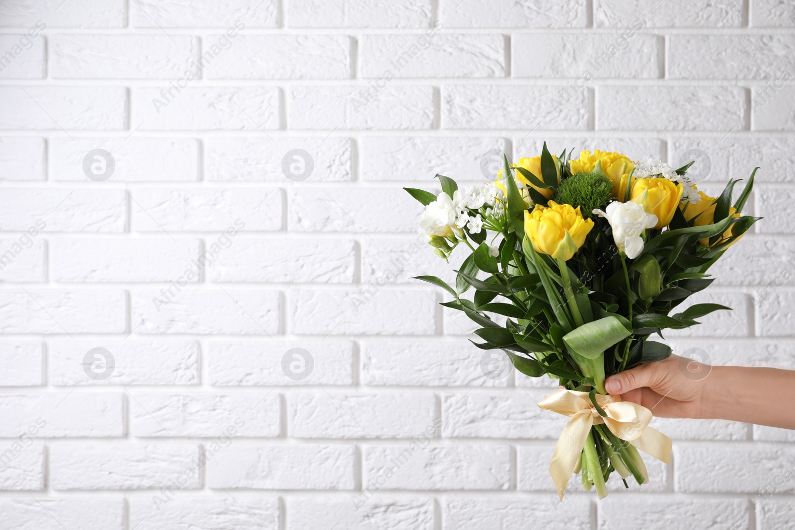 Photo of Woman with bouquet of beautiful peony tulips near white brick wall, closeup. Space for text