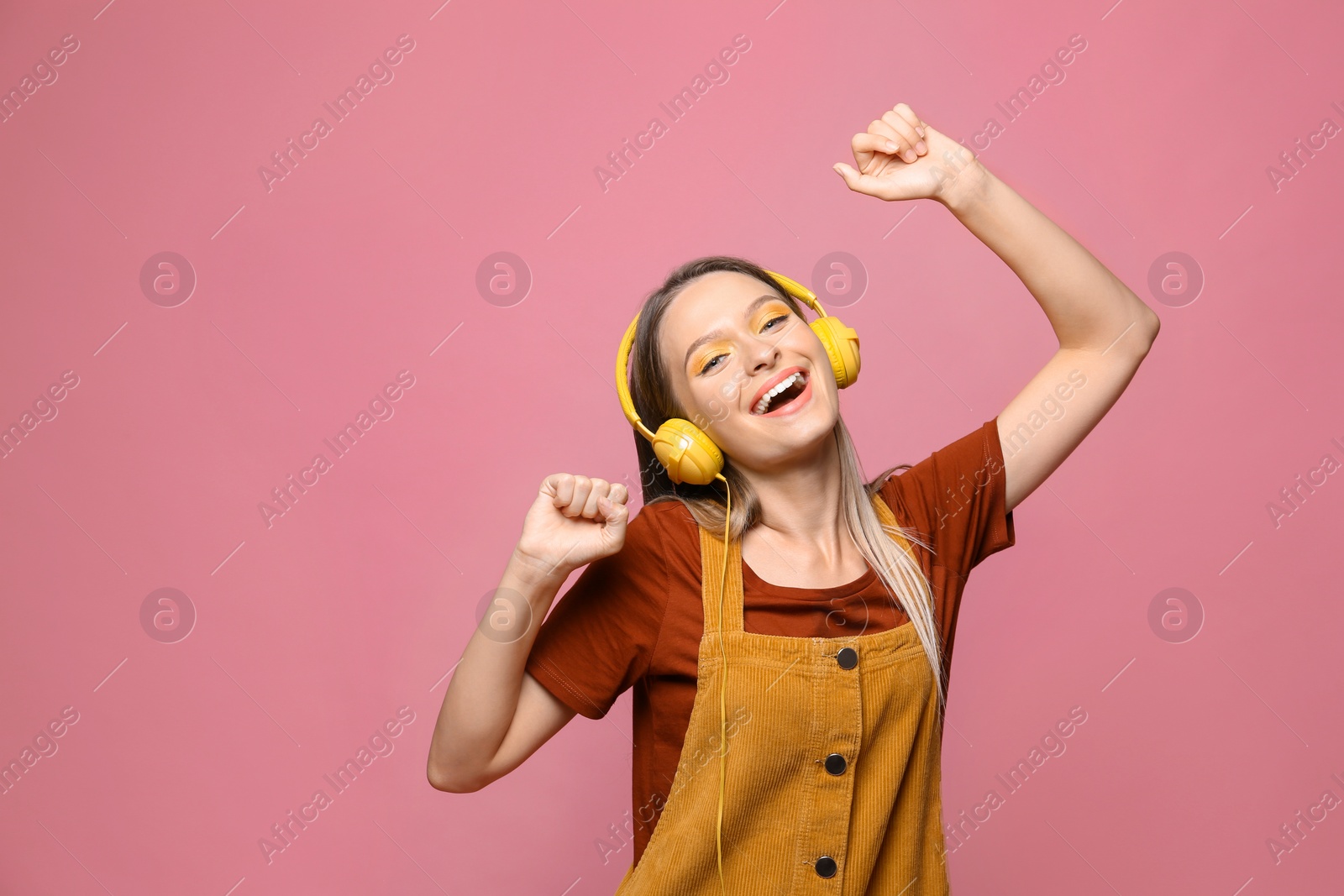 Photo of Happy teenage girl with headphones on pink background