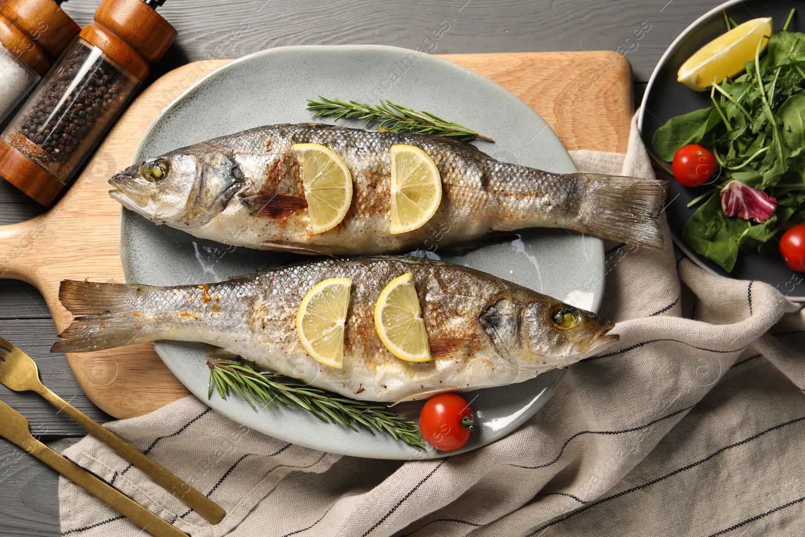 Photo of Delicious baked fish served on grey wooden table, top view