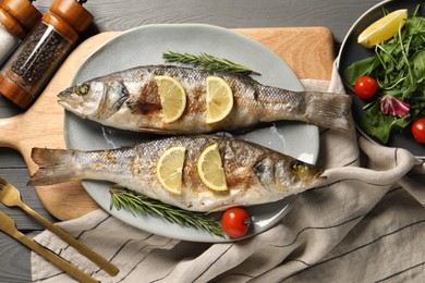 Delicious baked fish served on grey wooden table, top view