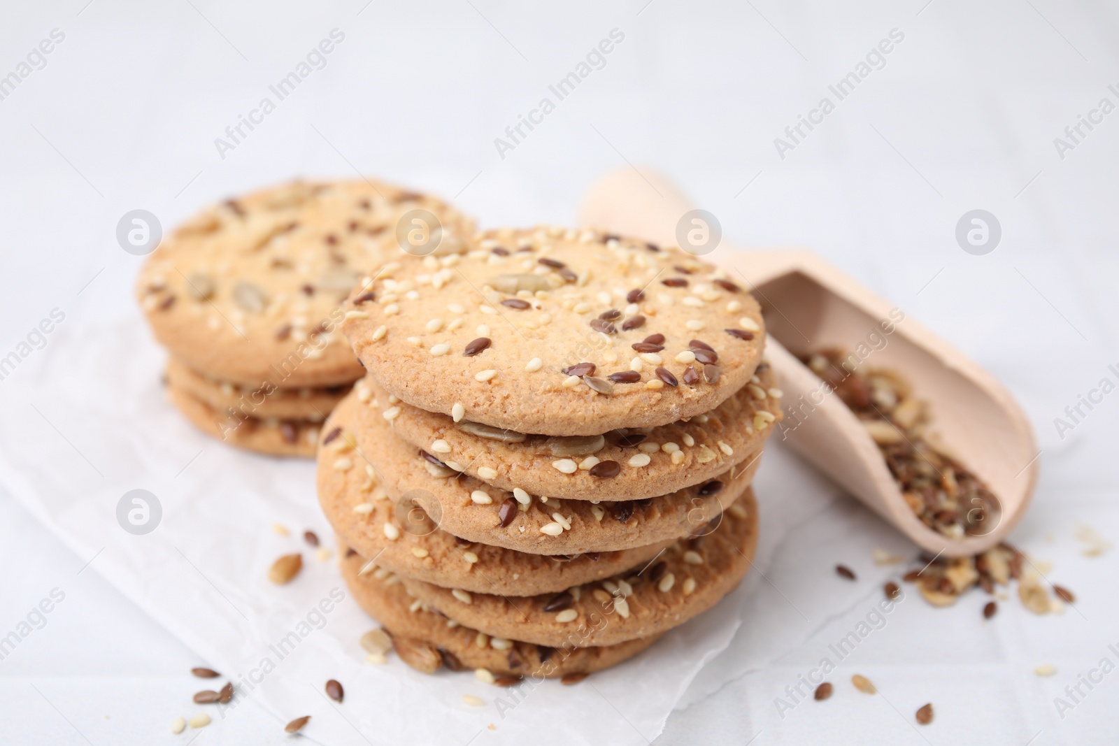 Photo of Cereal crackers with flax and sesame seeds on white tiled table, closeup