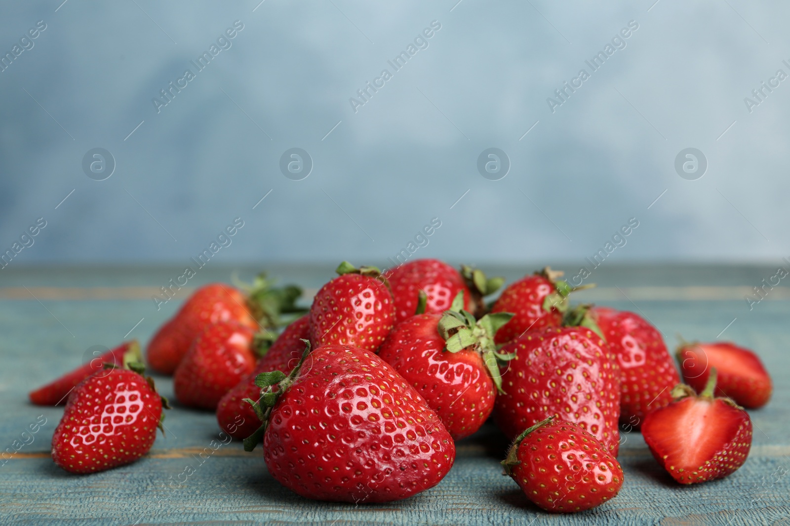 Photo of Delicious ripe strawberries on blue wooden table, closeup