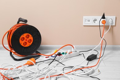 Extension cord reel plugged into socket on white floor indoors. Electrician's equipment