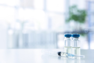 Photo of Vials and syringe with medicine on blurred background. Vaccination concept