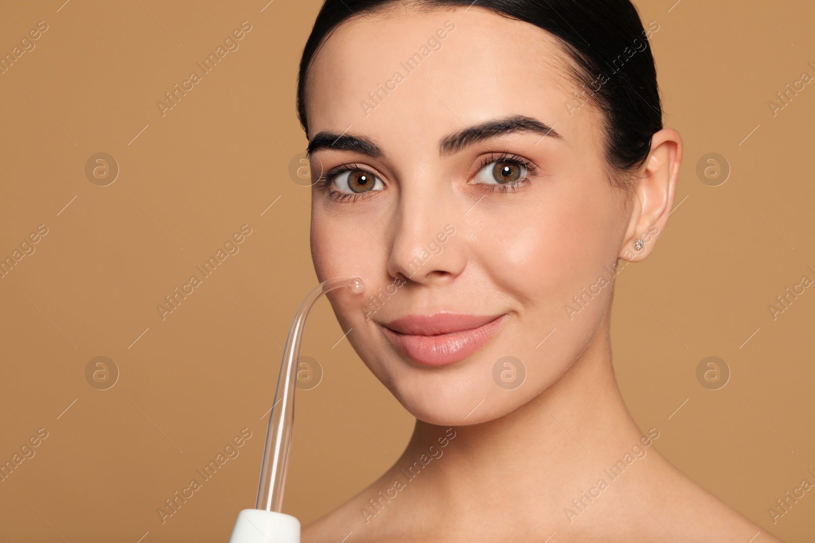 Photo of Woman using high frequency darsonval device on beige background. Space for text