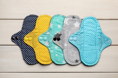 Photo of Many reusable cloth menstrual pads on white wooden table, flat lay