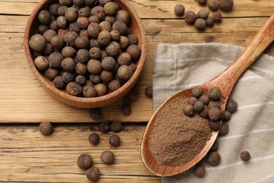 Photo of Aromatic allspice pepper grains in bowl, powder and spoon on wooden table, top view