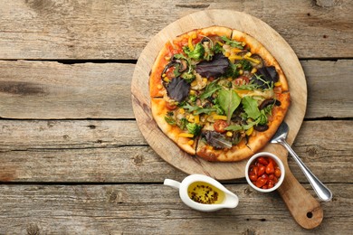 Photo of Delicious vegetarian pizza served on wooden table, top view. Space for text