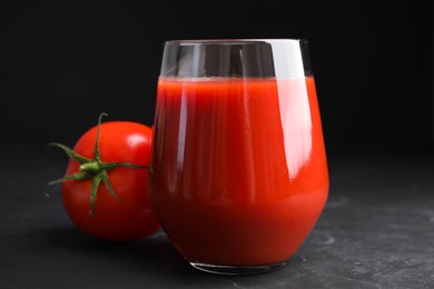 Photo of Delicious fresh tomato juice on black table, closeup