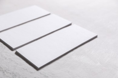 Blank business cards on light textured table, closeup. Mockup for design