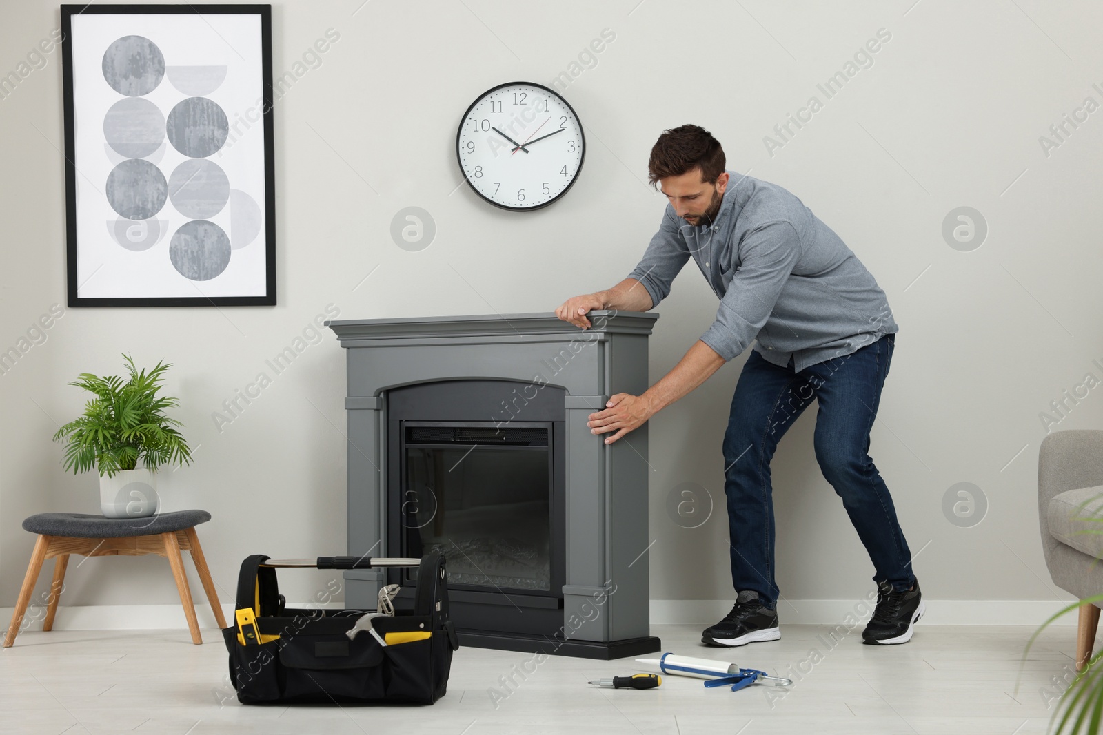 Photo of Man installing electric fireplace near wall in room