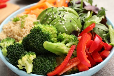 Photo of Delicious vegan bowl with bell peppers, avocados and broccoli on table, closeup