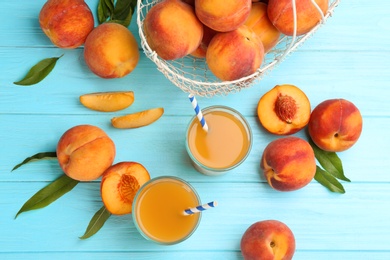 Photo of Natural peach juice and fresh fruits on light blue wooden table, flat lay