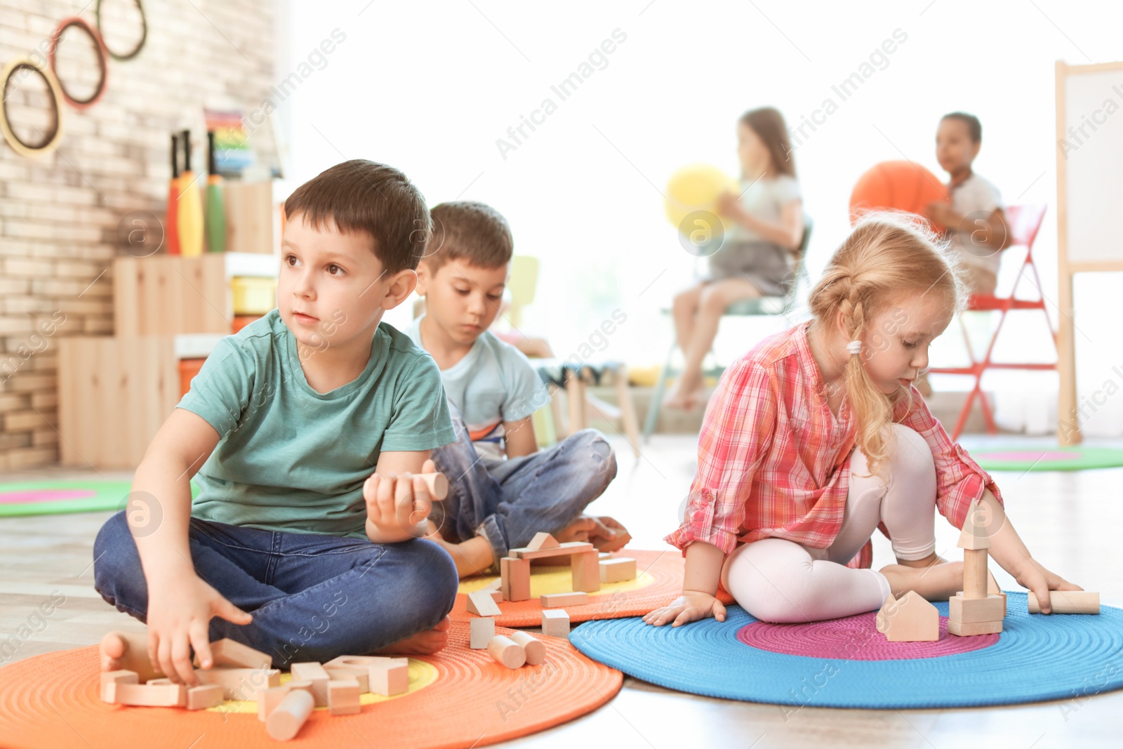 Photo of Cute little children playing with wooden blocks indoors