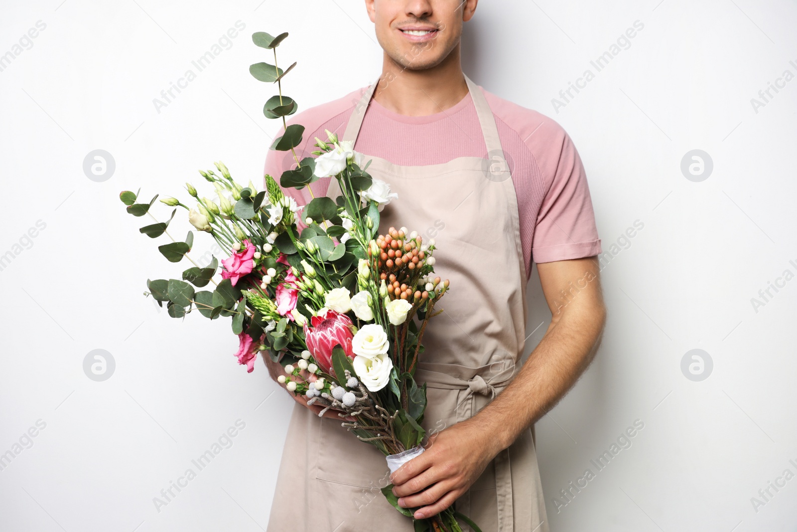 Photo of Florist with beautiful bouquet on light background, closeup