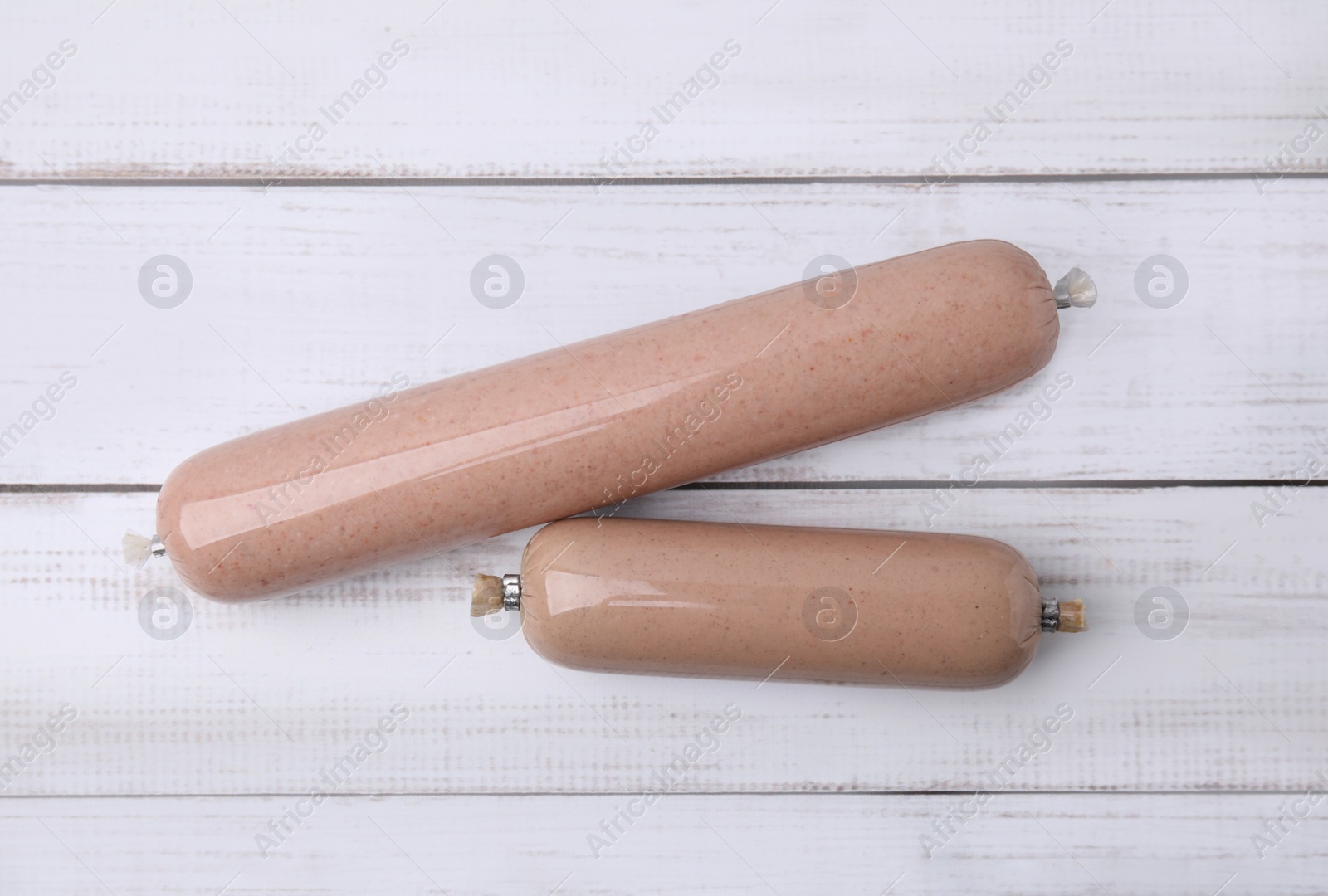 Photo of Delicious liver sausages on white wooden table, flat lay