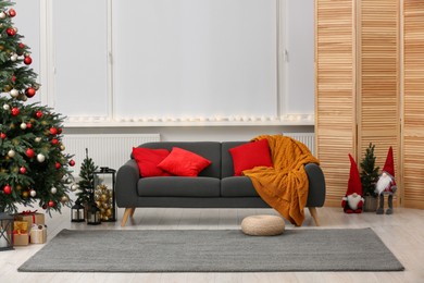 Photo of Soft sofa near Christmas tree and accessories in stylish room. Interior design