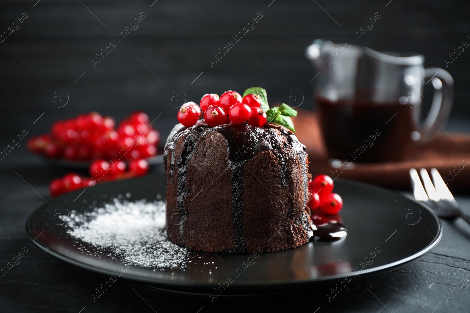 Photo of Delicious warm chocolate lava cake with mint and berries on dark grey table