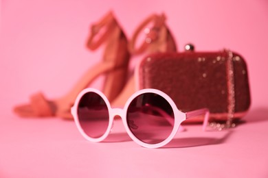Photo of Stylish bright sunglasses on pink background, closeup