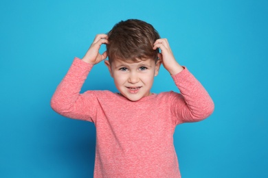 Photo of Little boy scratching head on color background. Annoying itch