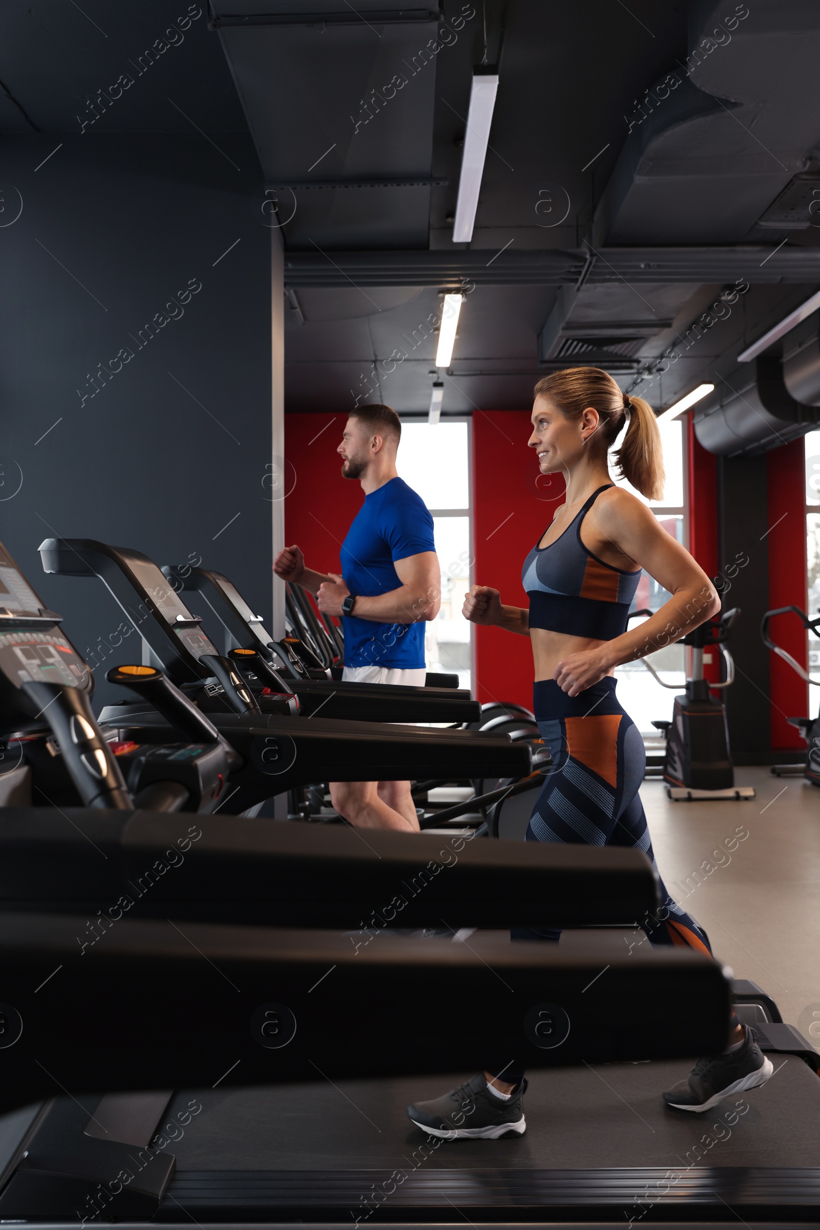 Photo of Beautiful couple training on treadmills in gym