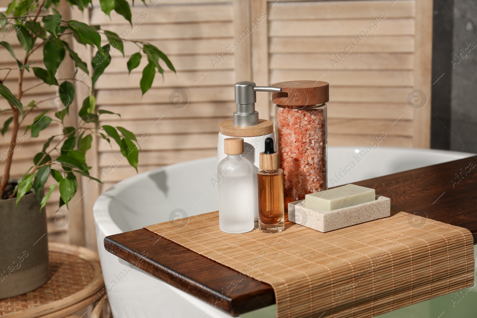 Photo of Wooden tray with spa products on bath tub in bathroom