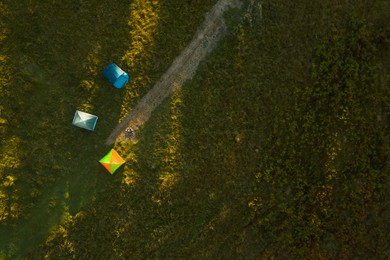 Image of Aerial view of camping tents and bonfire on green meadow