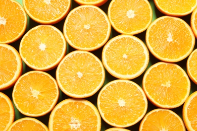 Halves of ripe oranges as background, top view