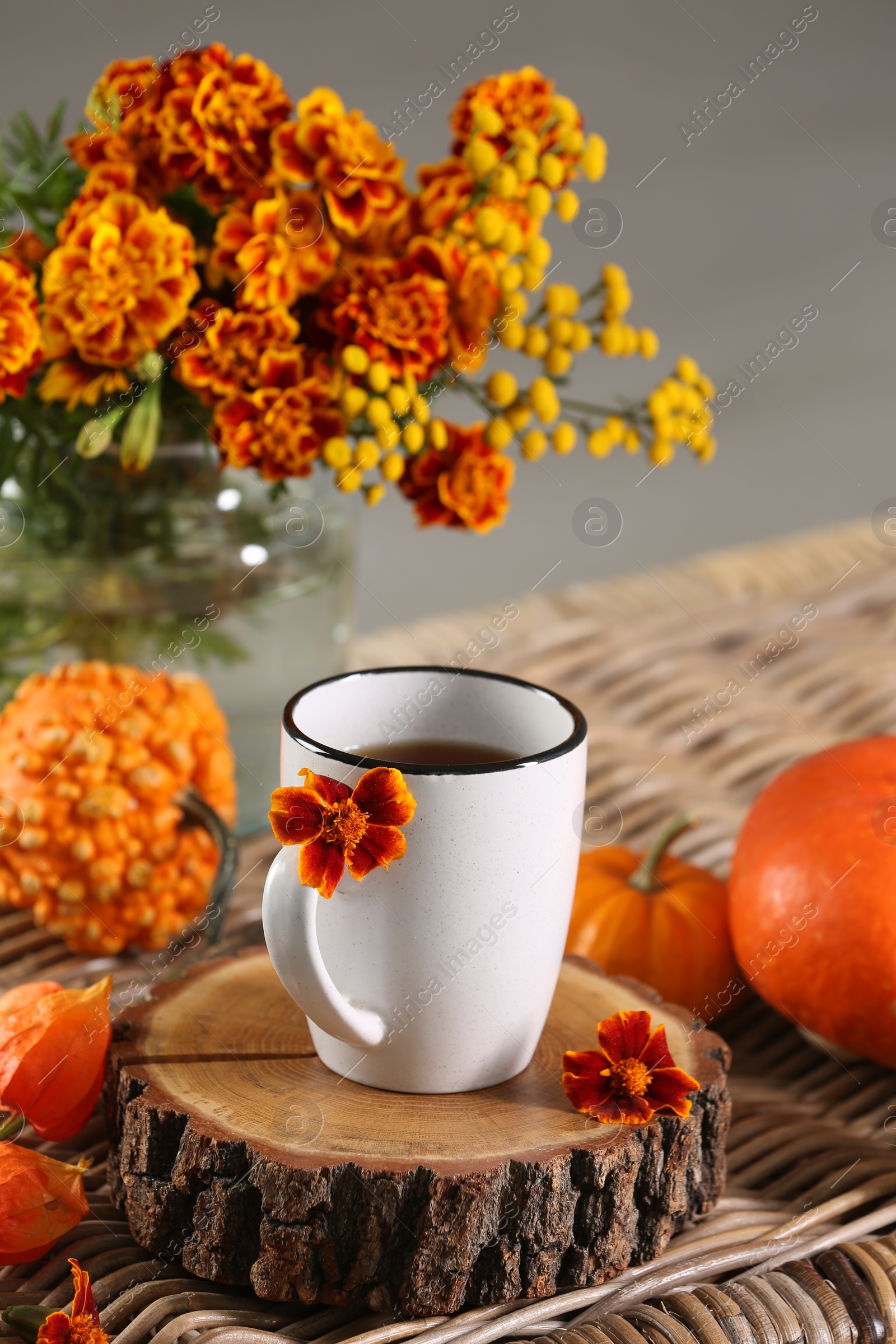 Photo of Beautiful autumn composition with cup of drink and flowers on wicker table