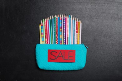 Case with different pencils and word Sale on blackboard, top view