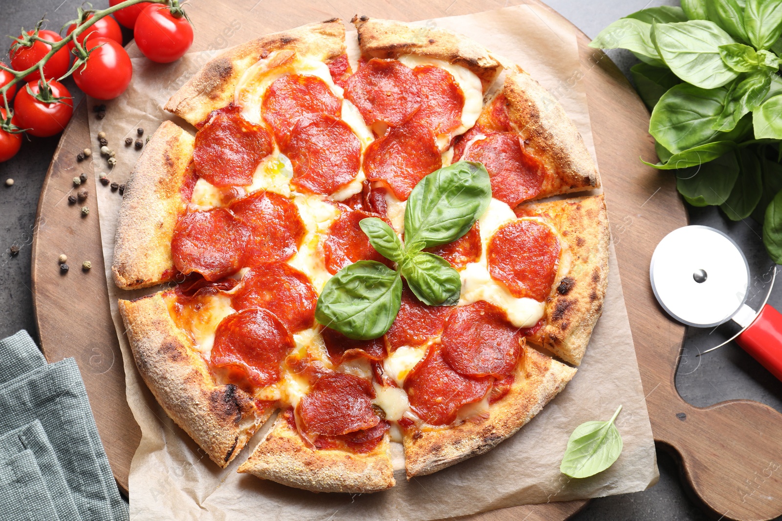 Photo of Tasty pepperoni pizza, cutter and ingredients on table, top view