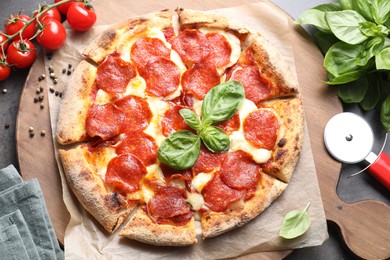 Photo of Tasty pepperoni pizza, cutter and ingredients on table, top view