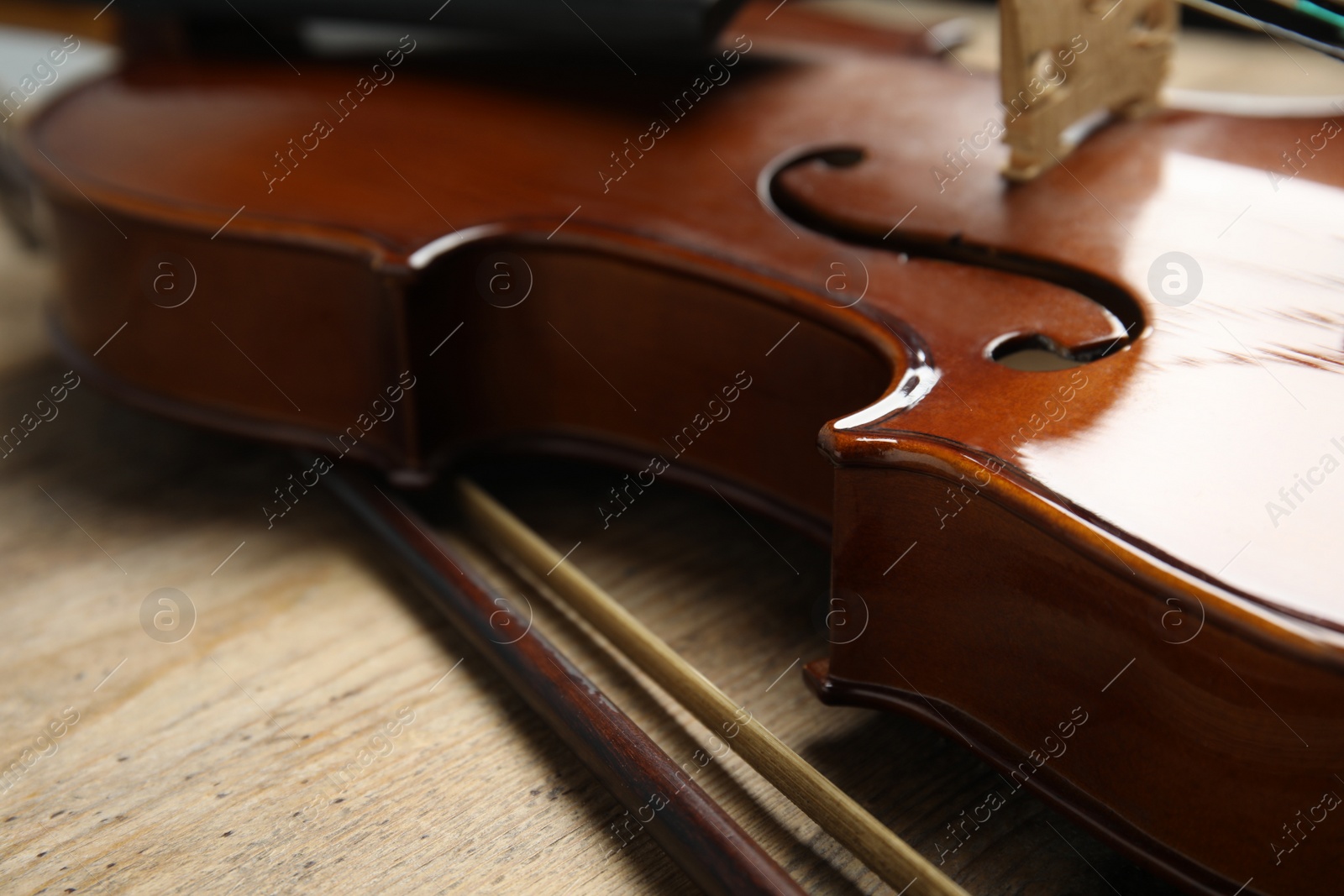 Photo of Beautiful violin and bow on wooden table, closeup