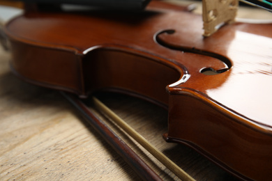 Beautiful violin and bow on wooden table, closeup