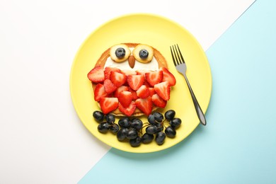 Creative serving for kids. Plate with cute owl made of pancakes, berries, cream, banana and almond on color background, top view