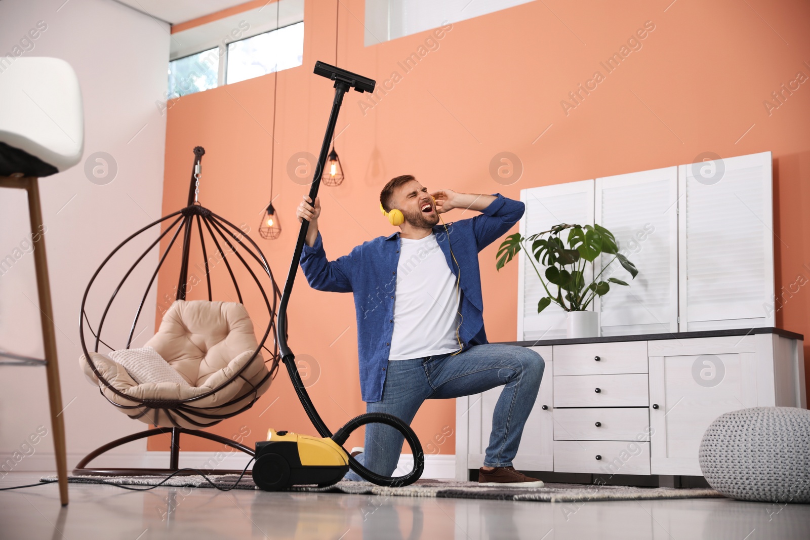 Photo of Young man having fun while vacuuming at home