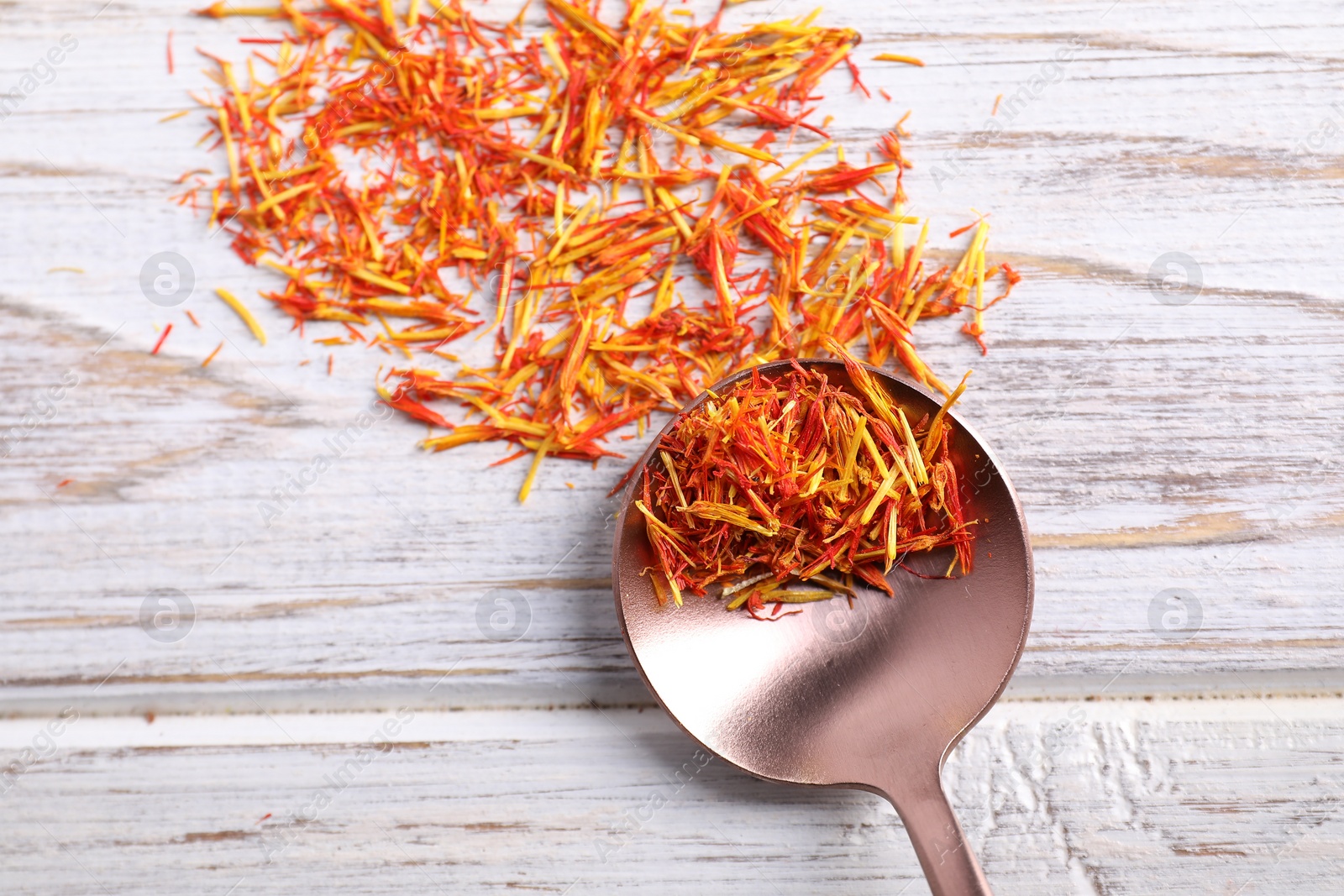 Photo of Aromatic saffron and spoon on wooden table, top view