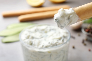 Photo of Bread stick with cucumber sauce on blurred background, space for text. Traditional Tzatziki